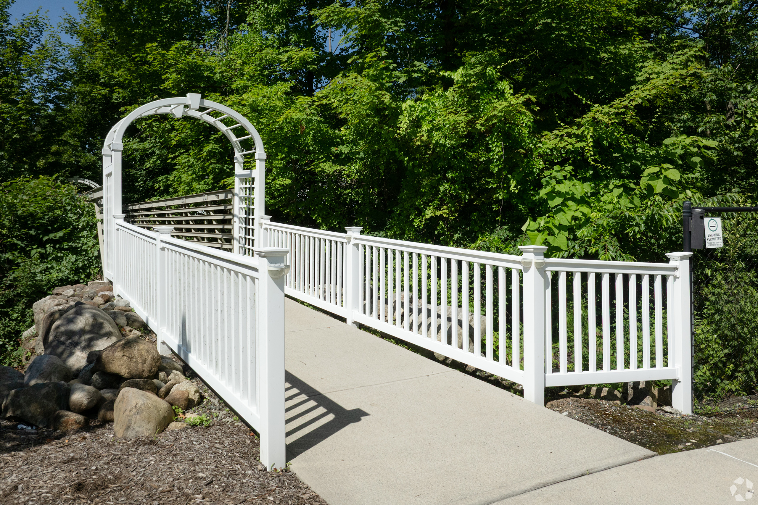 White trellis arbor walkway on landscaped grounds